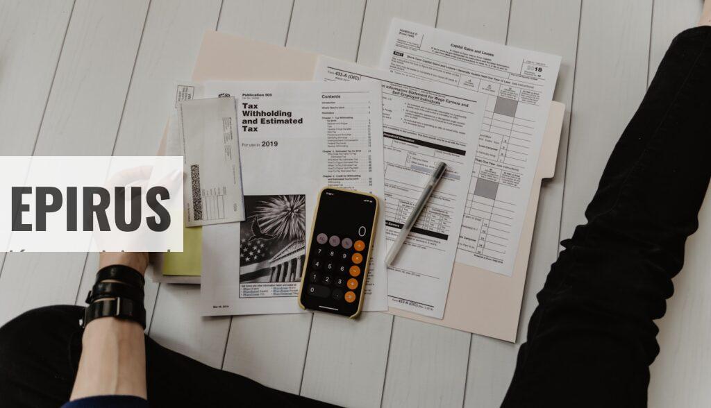 person holding paper near pen and calculator