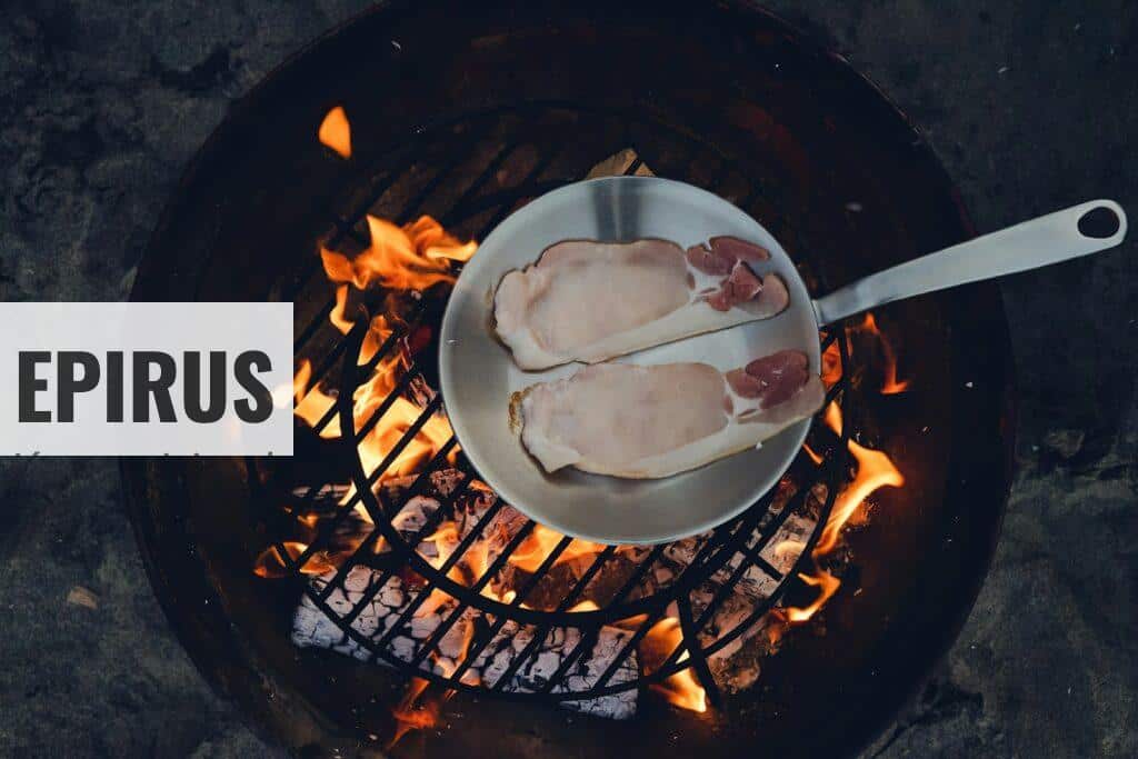 person cooking steak on charcoal gril